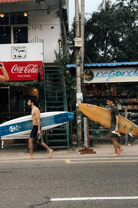 Two surfers walking to the beach with their boards