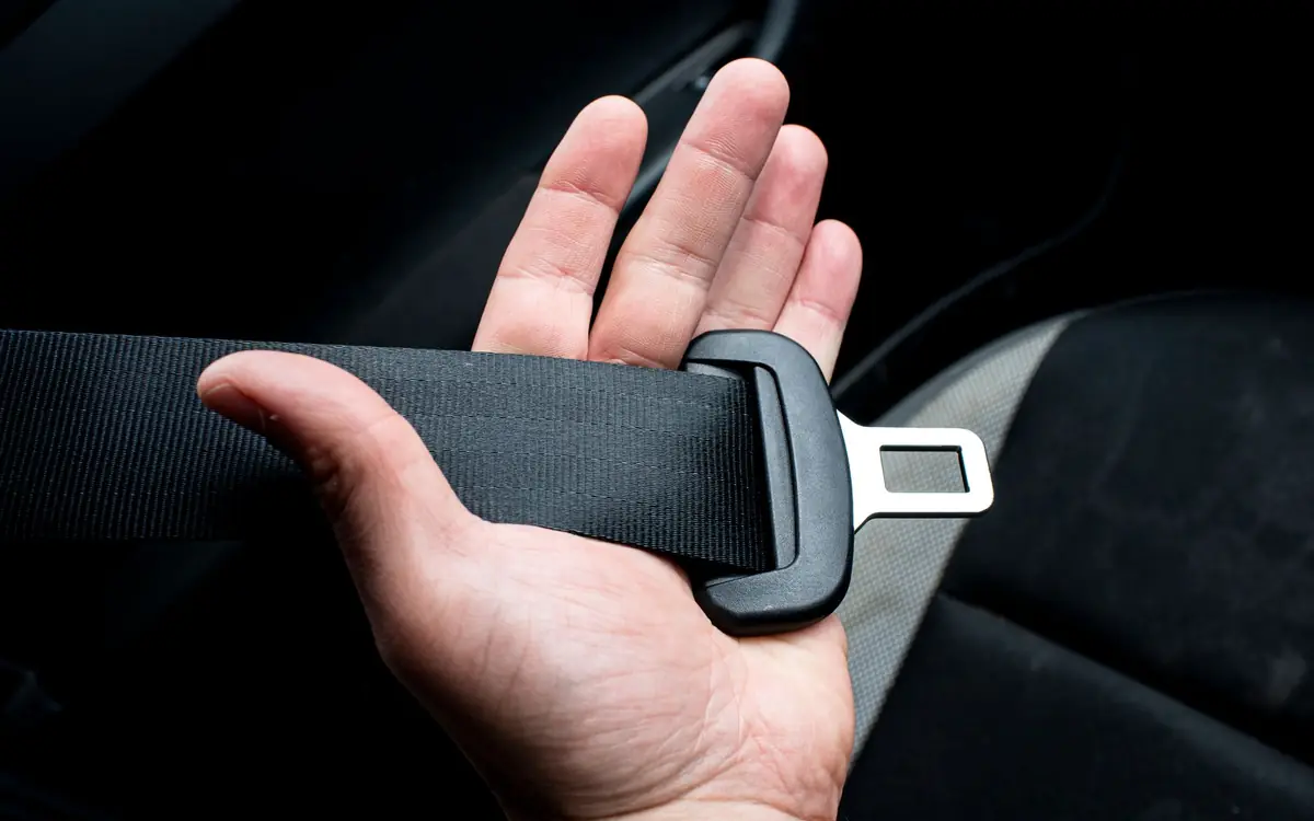 A hand holding a car seat belt